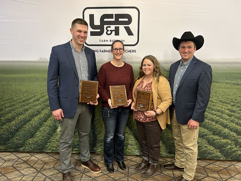 four people standing together holding plaques